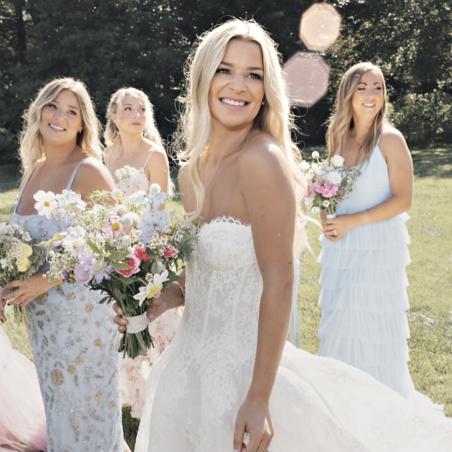 Smiling bride in a lace gown holding a wildflower bouquet
